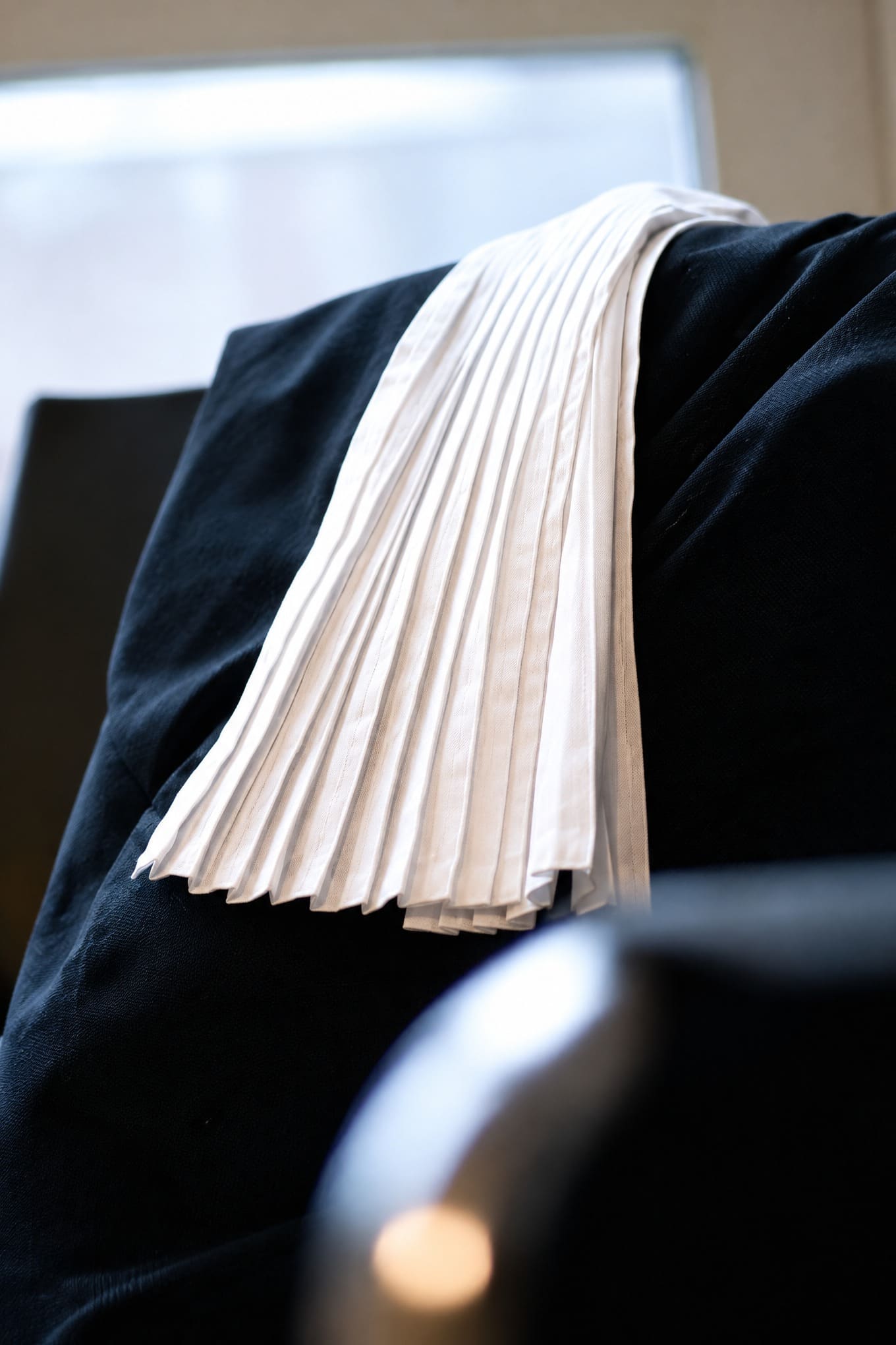 Toga met witte bef van de advocaat, over een stoel in de kantoorruimte